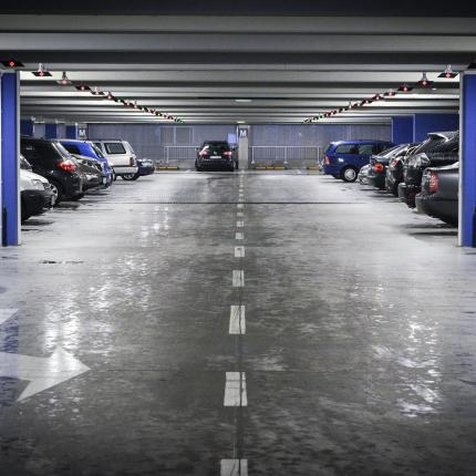Photo d'un parking souterrain avec des voitures de stationnées de part et d'autres